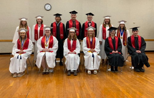 Class of 2022 in caps & gowns seated on stage.